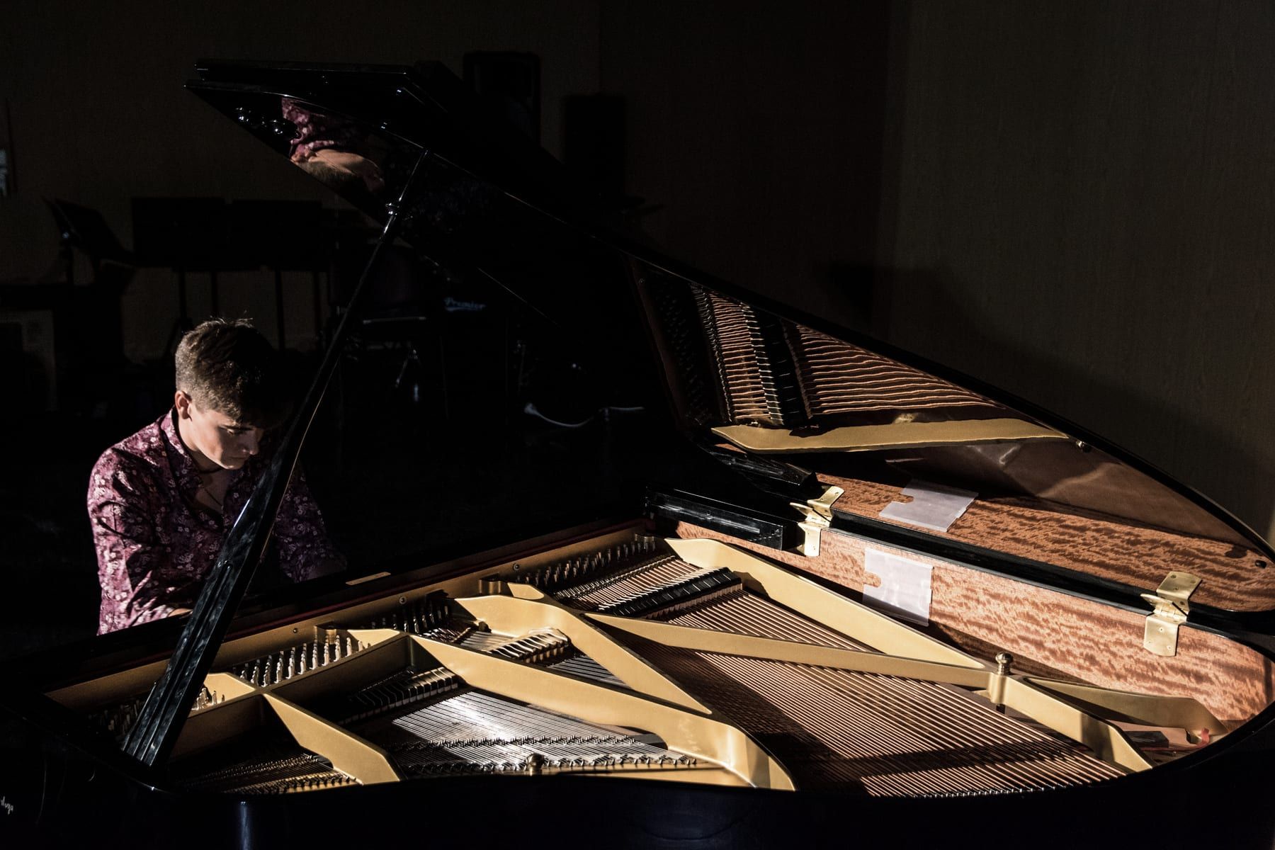 El interior iluminado de un piano de cola, con Javier Cecilia al teclado en penumbra